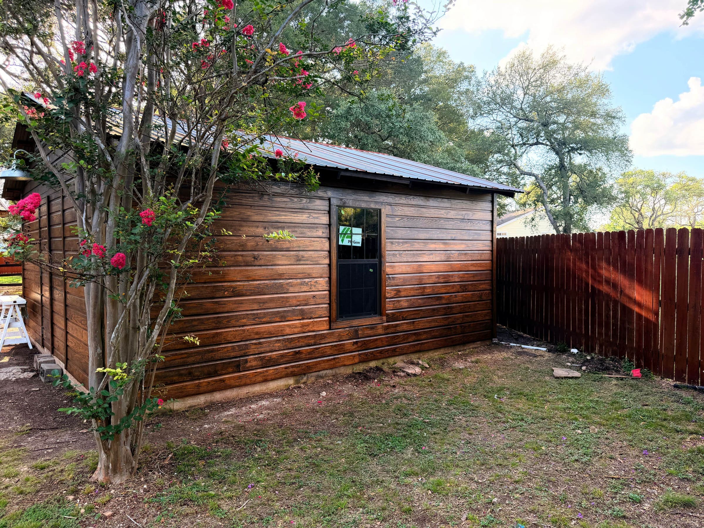 Stained wood siding and new privacy fence on a backyard remodel — Austin, TX